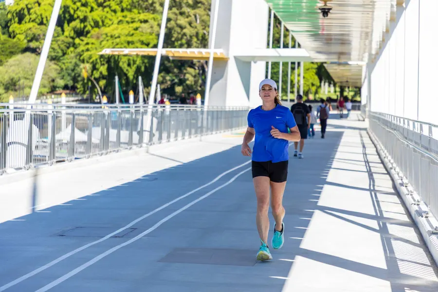 Runners crossing the Kangaroo Point pedestrian bridge at sunrise